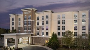 A multi-story hotel with a prominent entrance, a covered driveway, and a parking area. - Homewood Suites by Hilton Concord Charlotte (Concord)