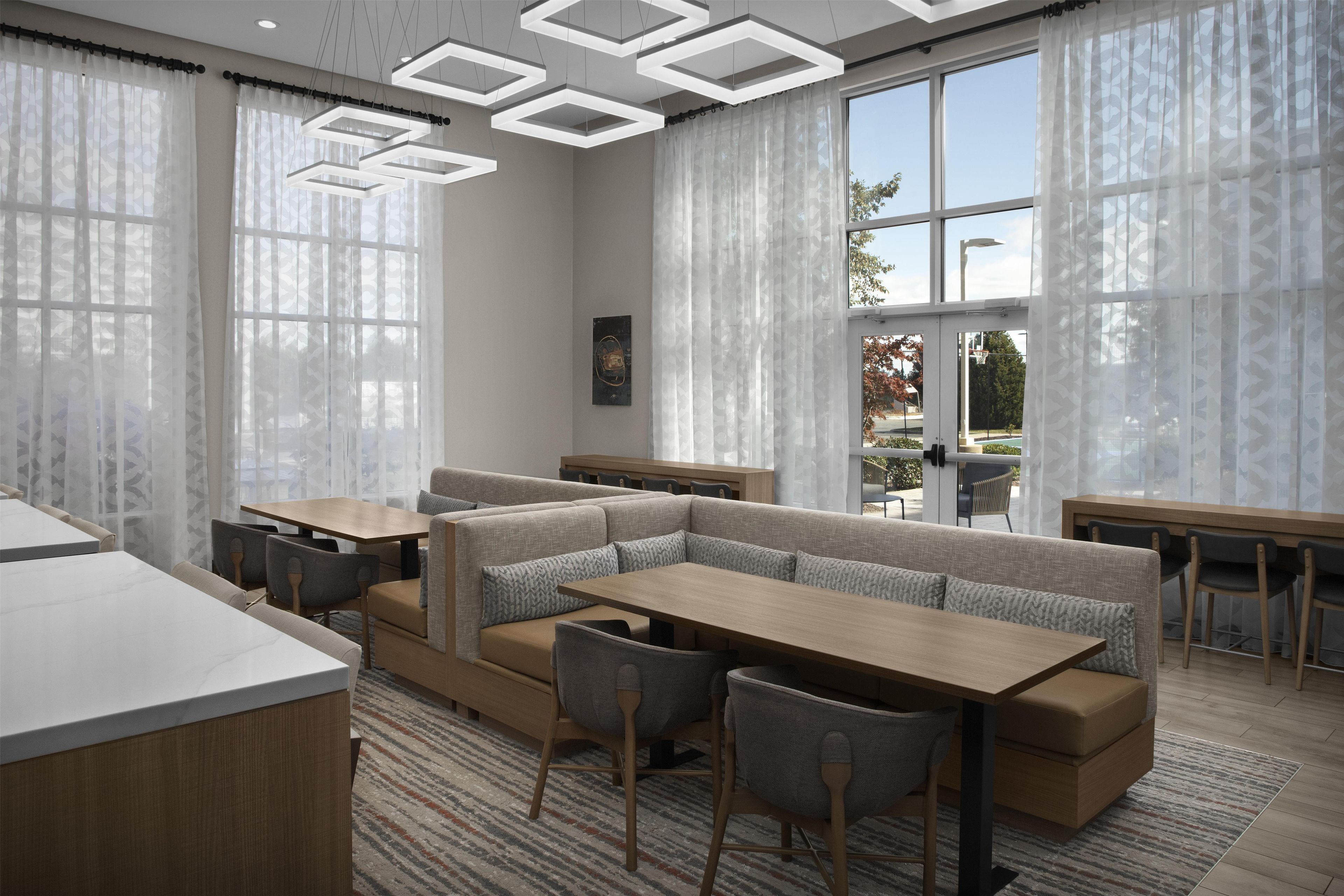 Un restaurante moderno con una zona de estar central, mesas y vistas al exterior.