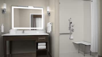 A modern bathroom with a large mirror, a sink, a shower, and a vanity with a towel rack.