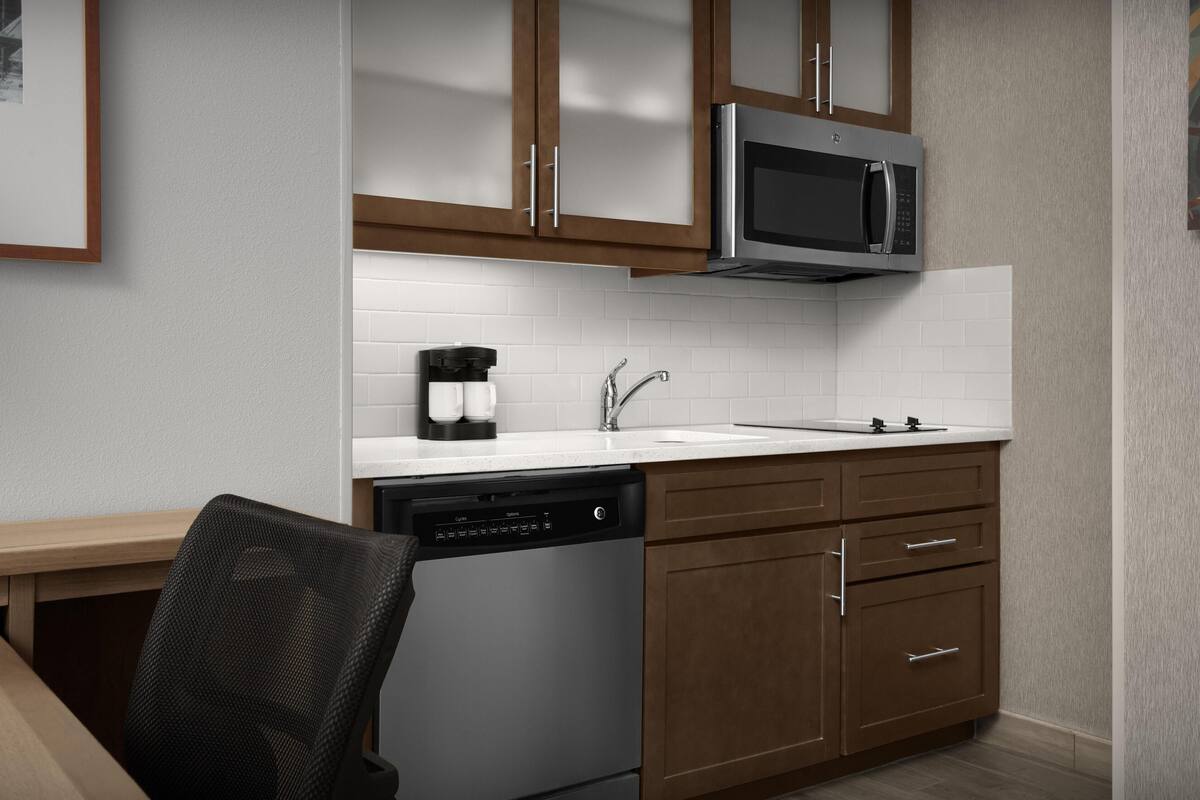 A modern kitchen with stainless steel appliances, wooden cabinets, and a dishwasher.