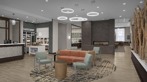 A hotel lobby with a reception desk, a 'SUITE SHOP', seating area with a sofa and chairs, a fireplace, and a decorative wooden wall. - Homewood Suites by Hilton Concord Charlotte (Concord)