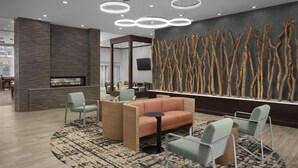 A modern lobby with a stone wall, a fireplace, seating area, and a wall-mounted art piece. - Homewood Suites by Hilton Concord Charlotte (Concord)