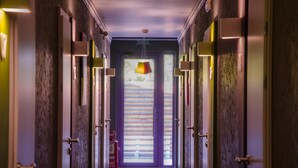 A hallway with doors on both sides, a fire extinguisher, and a hanging light fixture. - Good Night Hotel (Odesa)