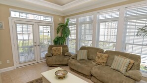 A living room with beige walls, a beige sofa, a white coffee table, and a large window with blinds. - Tuscan Ocean Vista C Holiday Home 8 bedroom By Affordable Large Properties (Myrtle Beach)