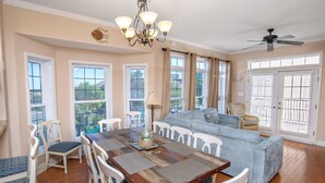 A spacious dining area with a wooden table and white chairs, a blue sofa, and a chandelier. - Tuscan Ocean Vista C Holiday Home 8 bedroom By Affordable Large Properties (Myrtle Beach)