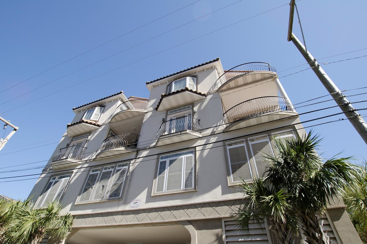 Un edificio de varios pisos con balcones, ventanas grandes y cielo despejado.