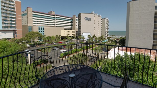 A hotel with a view of the ocean, featuring a parking lot, a pool area, and a dining area with outdoor seating. - Tuscan Ocean Vista C Holiday Home 8 bedroom By Affordable Large Properties (Myrtle Beach)