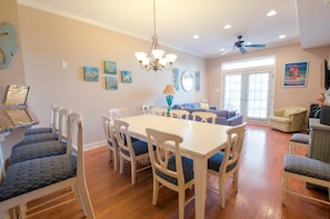 A dining area with a white table and chairs, a chandelier, and artwork on the walls.