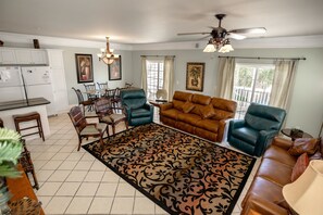 A spacious living room with a brown leather sofa, blue armchairs, and a dining area with wooden chairs and a table. - Bermuda Breeze D Holiday Home 8 bedroom By Affordable Large Properties (North Myrtle Beach)
