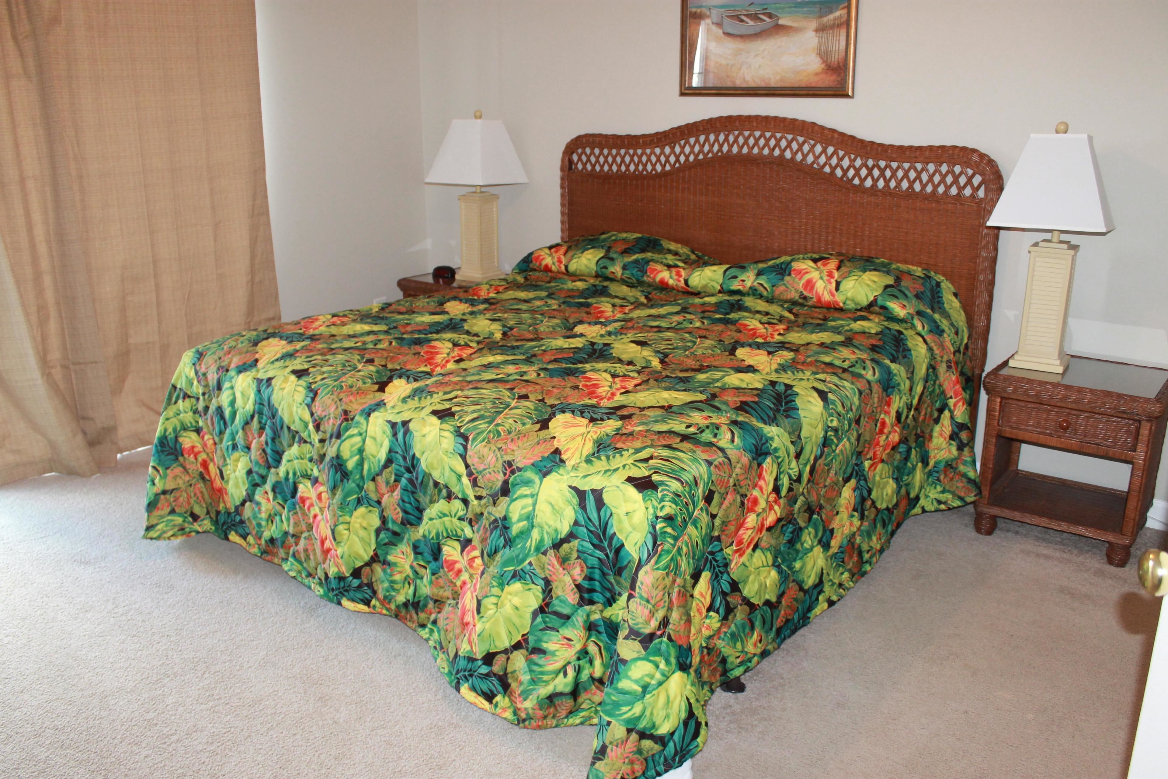 A bed with a floral bedspread, two bedside tables with lamps, and a curtain on the left.