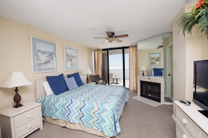 A hotel room with a bed, a TV, a fireplace, and a balcony with a view.