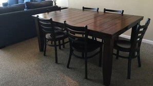A dining area with a wooden table and six chairs, a blue sofa, and a lamp. - The Palms 1701 Villa 4 bedroom By Affordable Large Properties (Myrtle Beach)