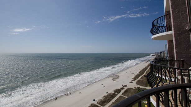A beach view from a balcony with a railing, ocean, and beachgoers. - The Palms 1701 Villa 4 bedroom By Affordable Large Properties (Myrtle Beach)