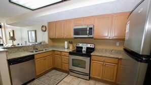 A kitchen with wooden cabinets, a stainless steel microwave, a dishwasher, and a stove. - The Palms 1701 Villa 4 bedroom By Affordable Large Properties (Myrtle Beach)