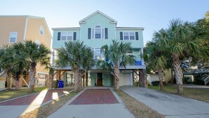 A two-story house with a red brick pathway leading to the front door, surrounded by palm trees.