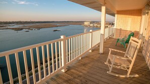 A wooden deck with a railing overlooking a body of water and a distant shoreline.