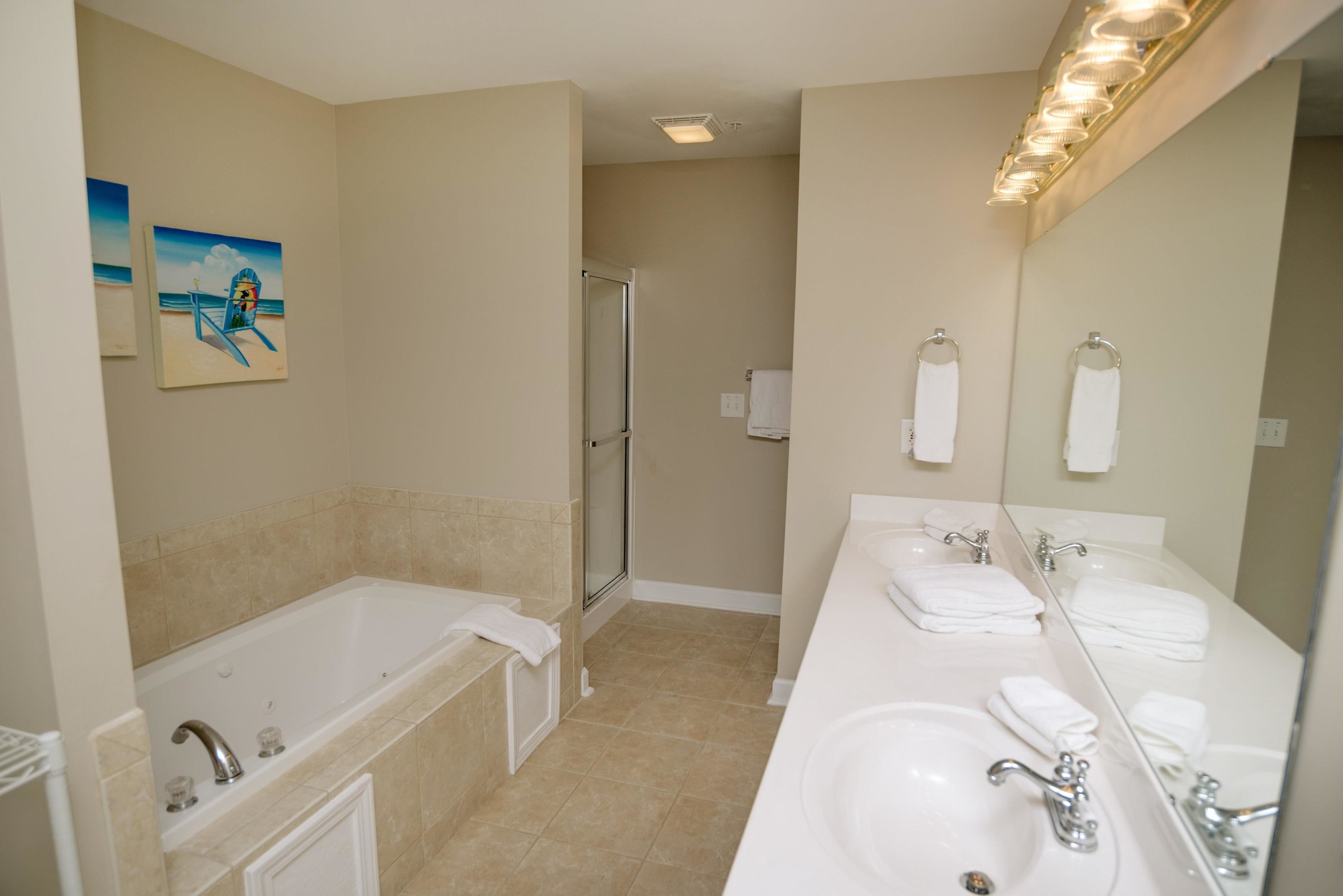 A modern bathroom with a bathtub, two sinks, and a large mirror.