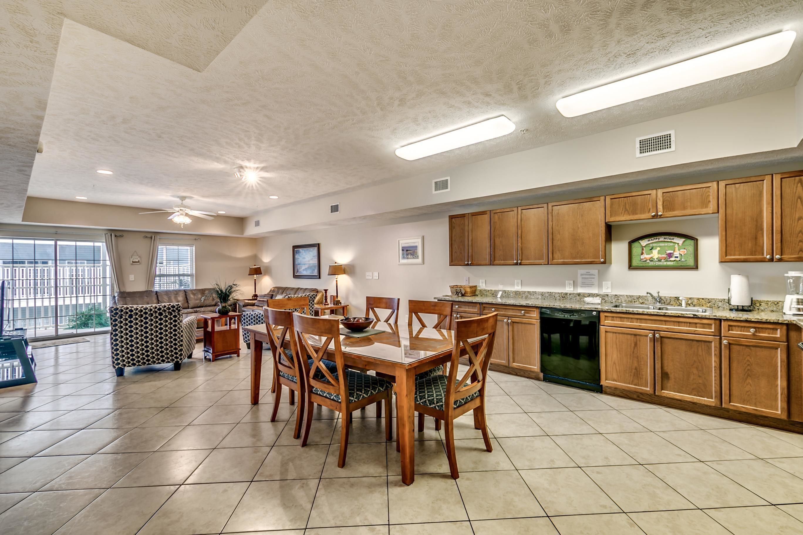 A spacious kitchen with wooden cabinets, a dining table with chairs, and a large window providing natural light.