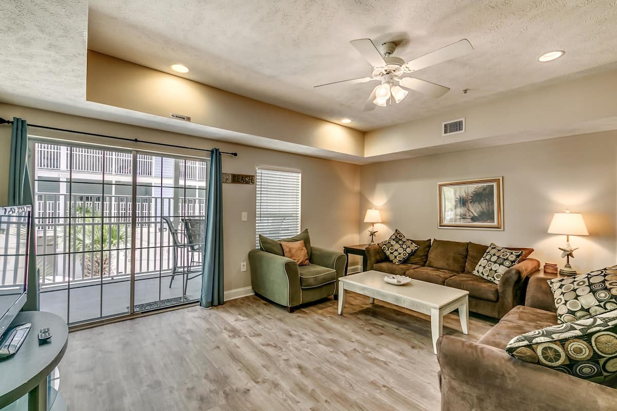 A living room with a ceiling fan, two couches, a coffee table, and a TV.