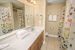 A bathroom with a sink, mirror, towel rack, and two hair dryers mounted on the wall. - Coconut Grove 204 Villa 5 bedroom By Affordable Large Properties (North Myrtle Beach)