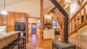 Une cuisine spacieuse avec des meubles en bois, un îlot central et une cheminée en pierre.