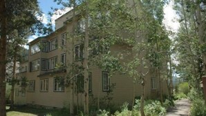 Un edifici residencial de diversos pisos amb una escala central, envoltat d'arbres i un camí.