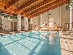 Una piscina coperta con soffitto in legno e pareti piastrellate.