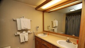 A bathroom with two sinks, a mirror, and towels hanging on the wall.