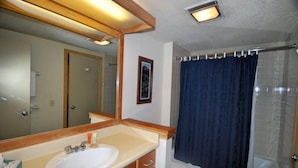 A bathroom with a sink, mirror, toilet, and shower curtain.