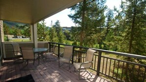 A wooden deck with outdoor furniture and a view of a forested area. - Pines Condominiums 3 Bedroom Apartment by Key to the Rockies (Keystone)