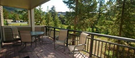A wooden deck with outdoor furniture and a view of a forested area.