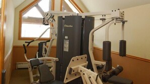 Une salle de sport équipée de machines Nautilus, dotée d’une fenêtre et d’un plafond en pente.