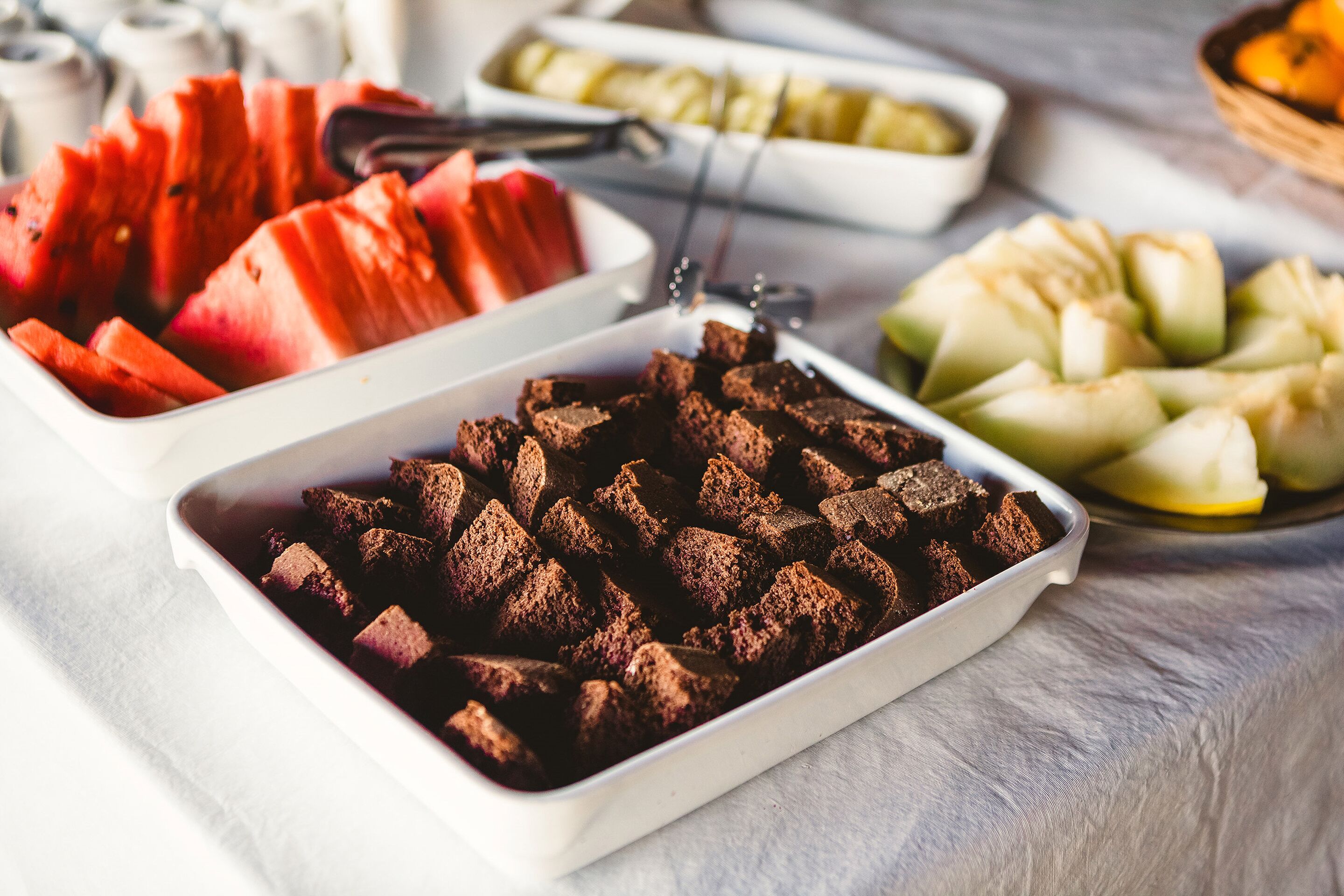 Un buffet proposant une variété de plats, notamment des pastèques, des pommes et des brownies.