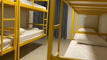 Una habitación con literas, cortinas y suelo de baldosas.