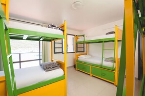 A dormitory room with bunk beds, a window, and a door.