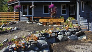 A two-story house with a red roof, large windows, and a front porch with a bench. - Ski Inn (Girdwood)