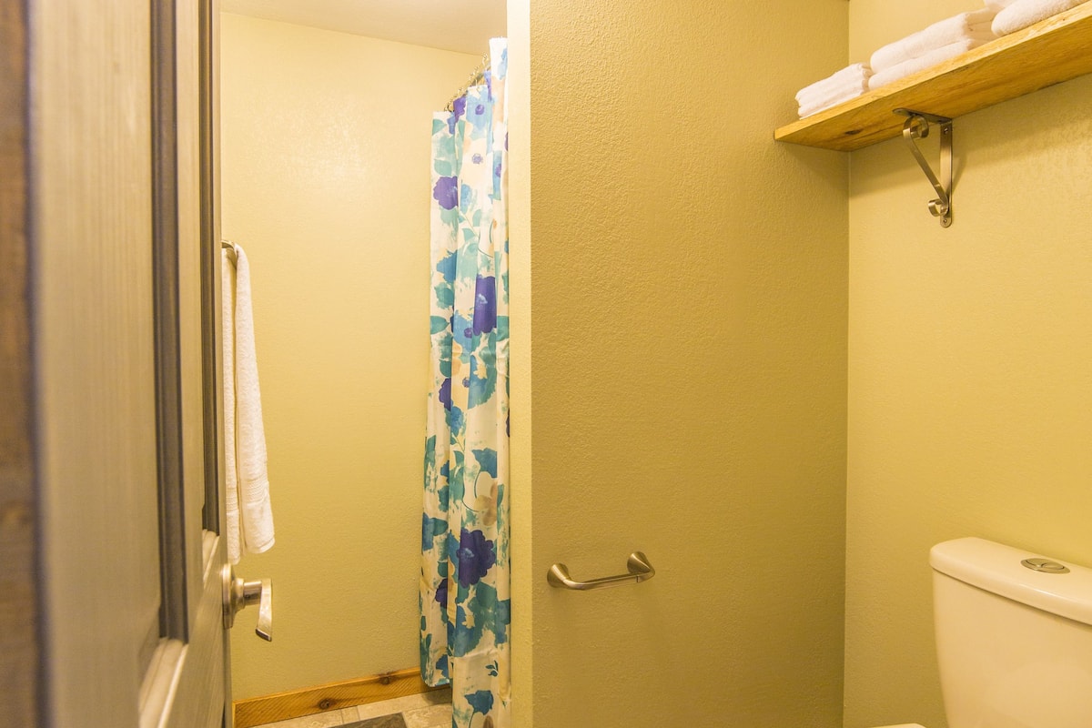 A bathroom with a toilet, a shower curtain, and a towel rack.