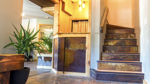 A staircase with a rustic design, a wooden bench, and a decorative floor pattern. - Ski Inn (Girdwood)