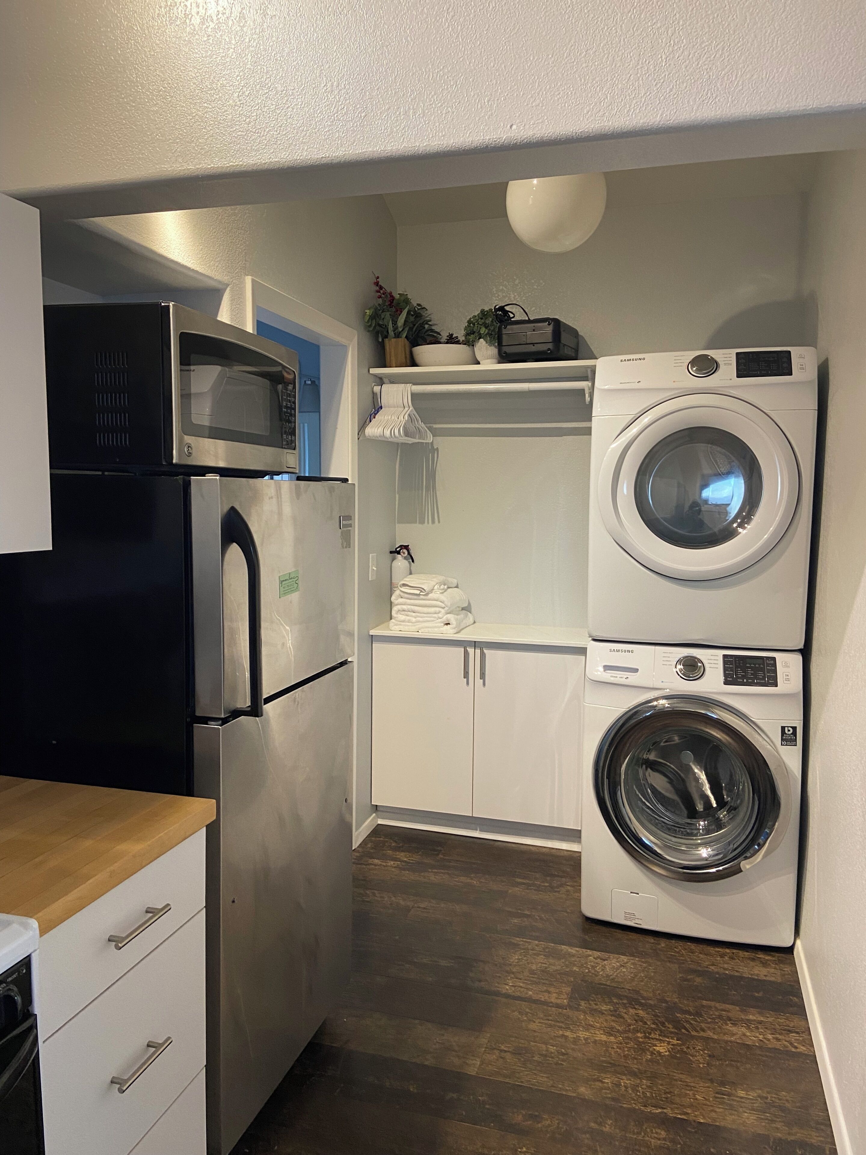 A compact kitchen with a microwave, refrigerator, and stacked washer-dryer unit.