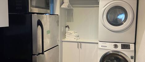 A compact kitchen with a microwave, refrigerator, and stacked washer-dryer unit.