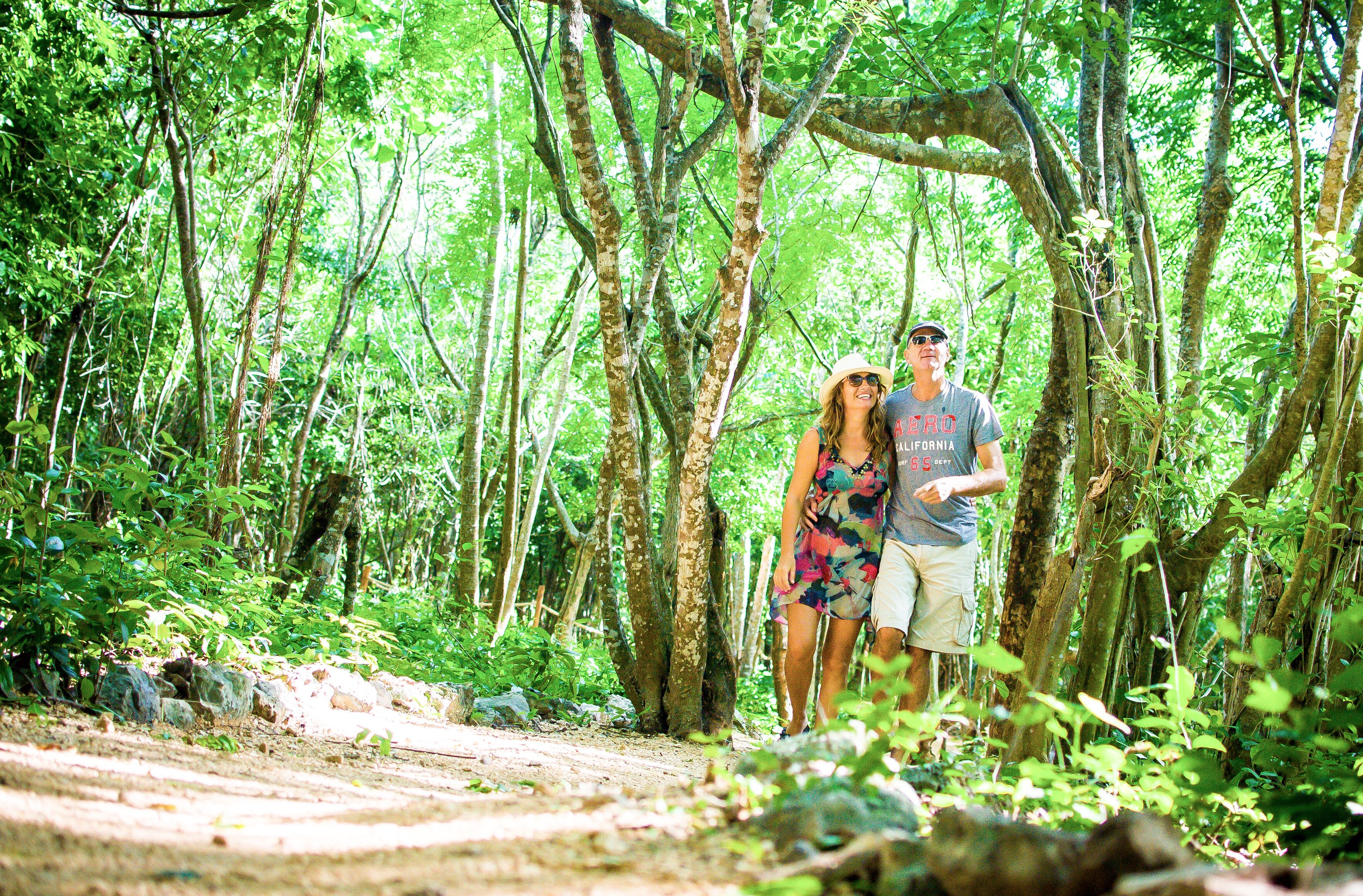 A couple standing on a dirt path in a forested area.