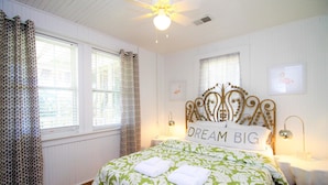 A neatly arranged bedroom with a large bed, a headboard with a 'DREAM BIG' sign, and a window with curtains. - E ARCTIC 412 2 Bedroom Holiday Home By My Ocean Rentals (Folly Beach)