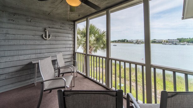 A covered outdoor area with a ceiling fan, a view of a body of water, and a row of chairs. - MARINERS CAY 45 2 Bedroom Holiday Home By My Ocean Rentals (Folly Beach)