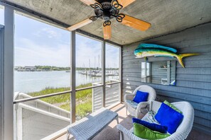 A balcony with wicker furniture, a ceiling fan, and a large fish decoration.
