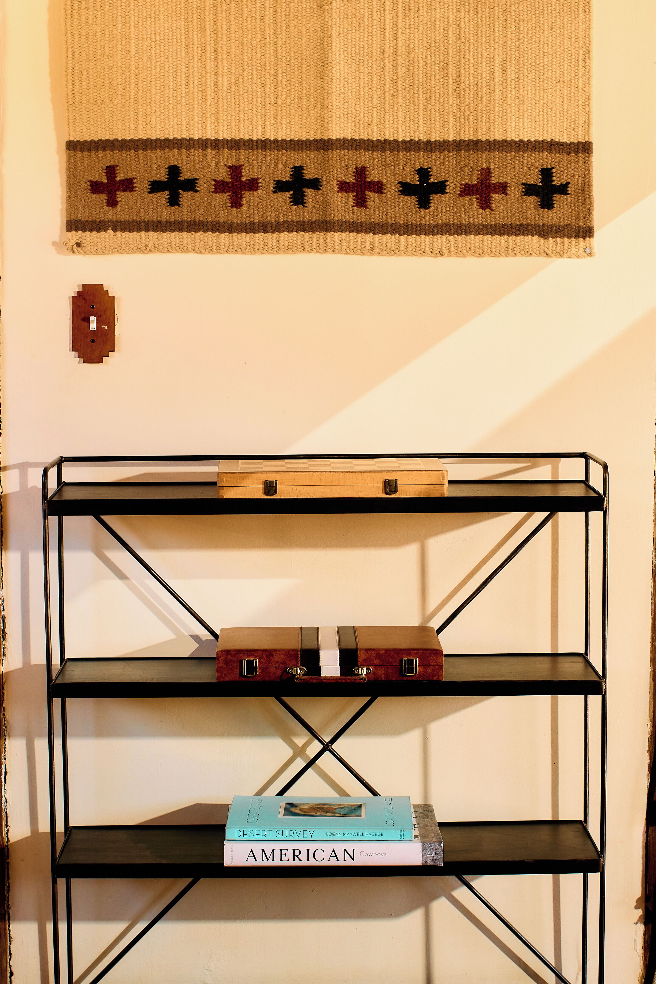 A black metal shelf unit with books and a wooden box on top.