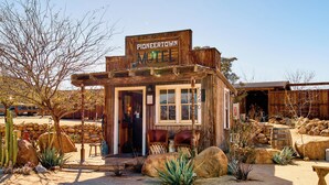A rustic motel with a wooden facade, a front desk, and a sign reading "Pioneer Town Motel."