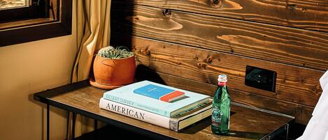 A hotel room with a wooden headboard, a bedside table with a potted plant, a lamp, and a bed with white linens.