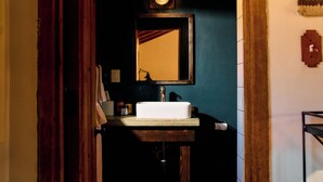 A bathroom with a white sink, a mirror, and a wooden door.