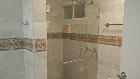 A shower with a glass door, a towel rack, and a showerhead.