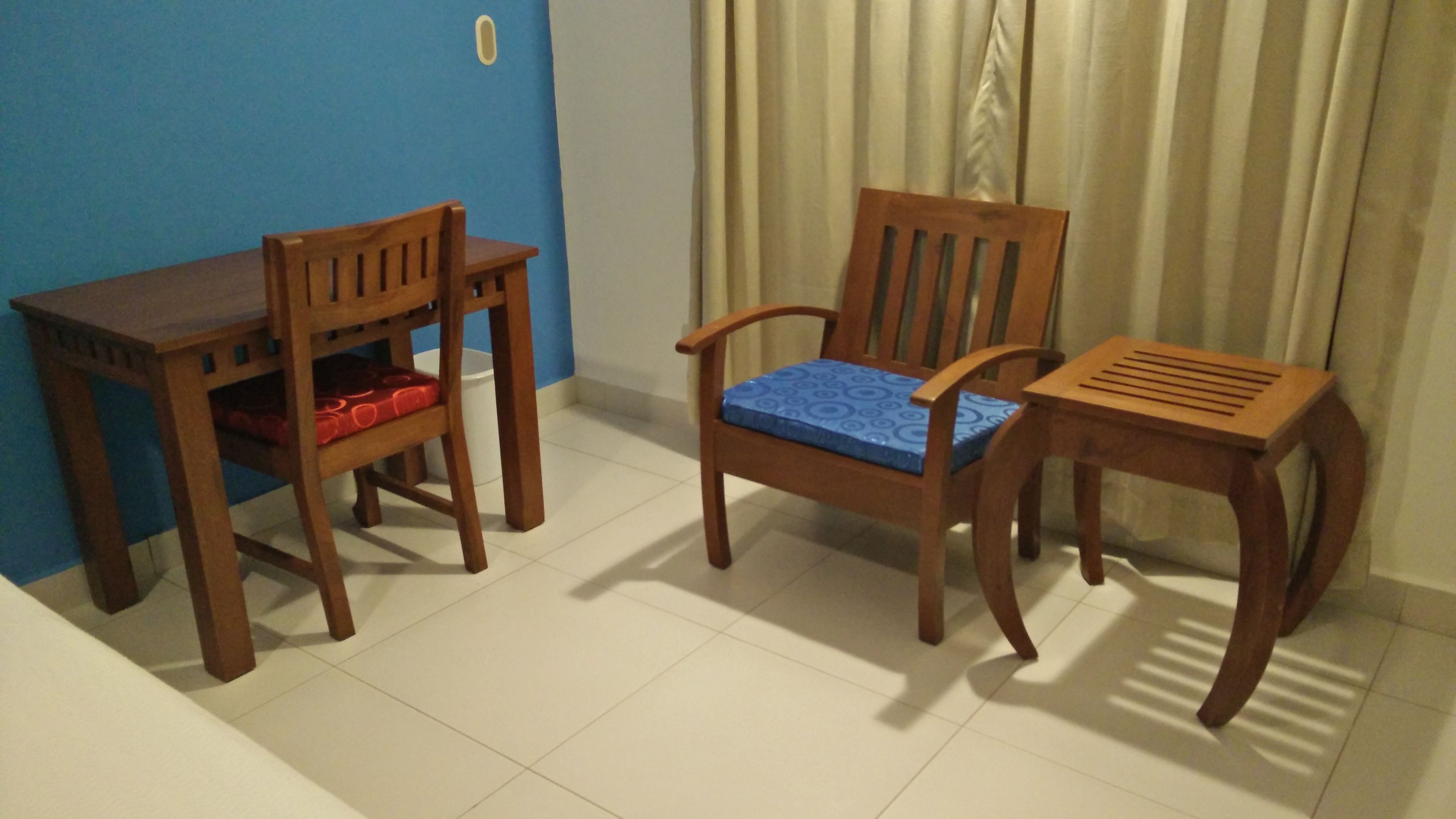 A room with a wooden table and two chairs, one with a blue cushion and another with a red cushion.
